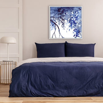 Abstract Watercolor canvas art print depicting branches and foliage in indigo-blue, in a bedroom with navy bed covers.