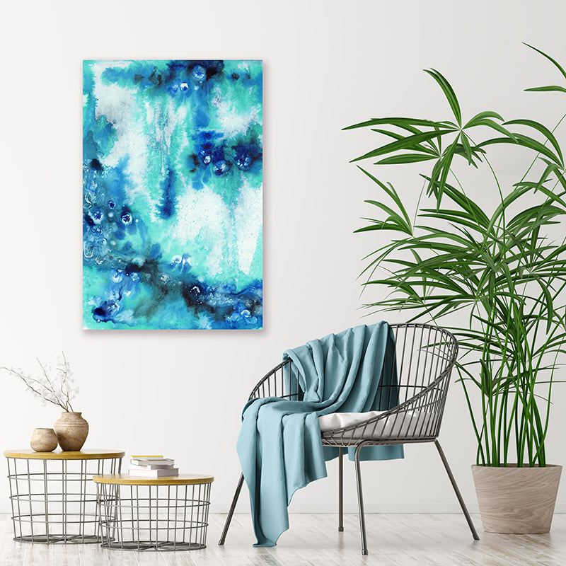 Abstract canvas art print in shades of aqua and sapphire blue, displayed in a minimalist tropical-style interior.