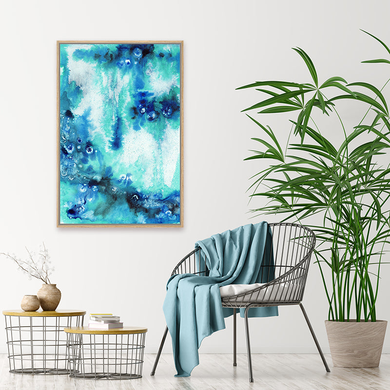 Framed canvas art print in shades of aqua and sapphire blue, displayed in a minimalist tropical-style interior.