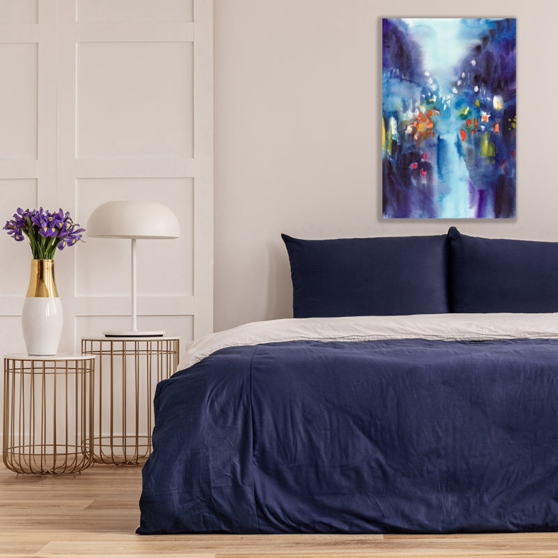 Art print featuring indigo blue, capturing the glow of street lights on a rainy night, above a bed with navy covers.