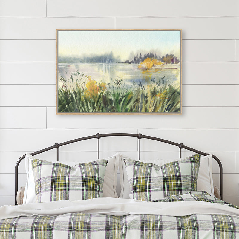 Canvas art print of a watercolour landscape artwork in green, gold and soft grey displayed in a country-style bedroom.