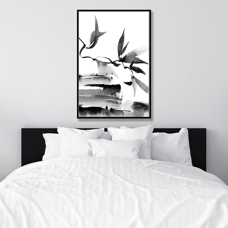 Black and white Japanese ink framed canvas art print of leaves and branches, in a minimalist bedroom.