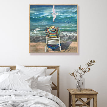 Retro beach canvas art print of a woman sitting on a beach gazing out towards a turquoise sea, a seagull gliding above her.
