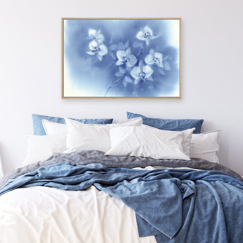 Watercolour framed canvas art print of white orchids set against a denim blue afternoon sky in a white and blue bedroom.