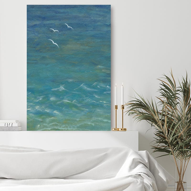 Art print of the sea from above, with seagulls and white breakers standing out against turquoise blue water in a romantic white bedroom.
